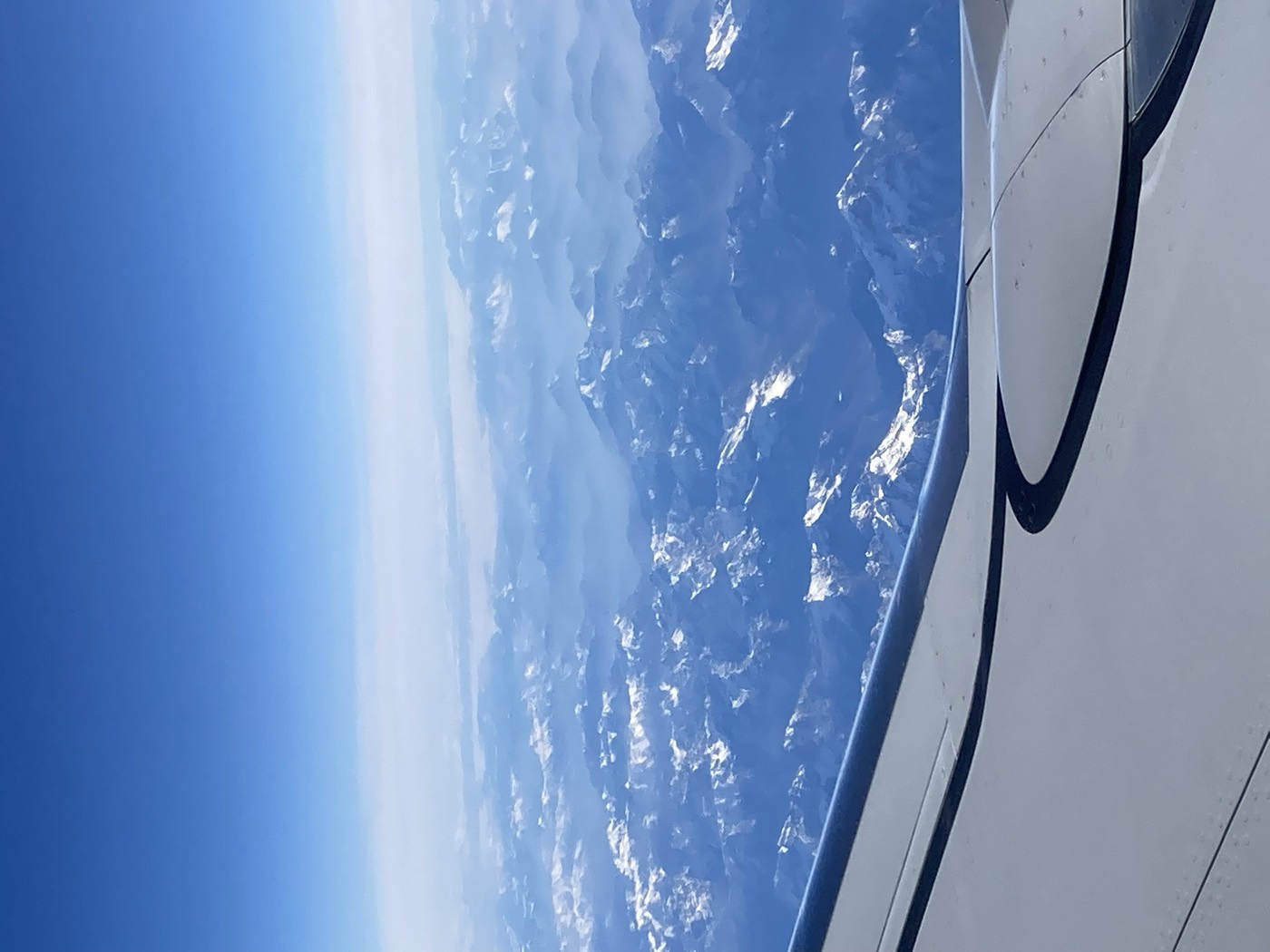an aeroplane wing over snow covered mountains