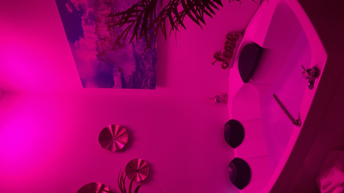 a corner bath in a room lit entirely pink