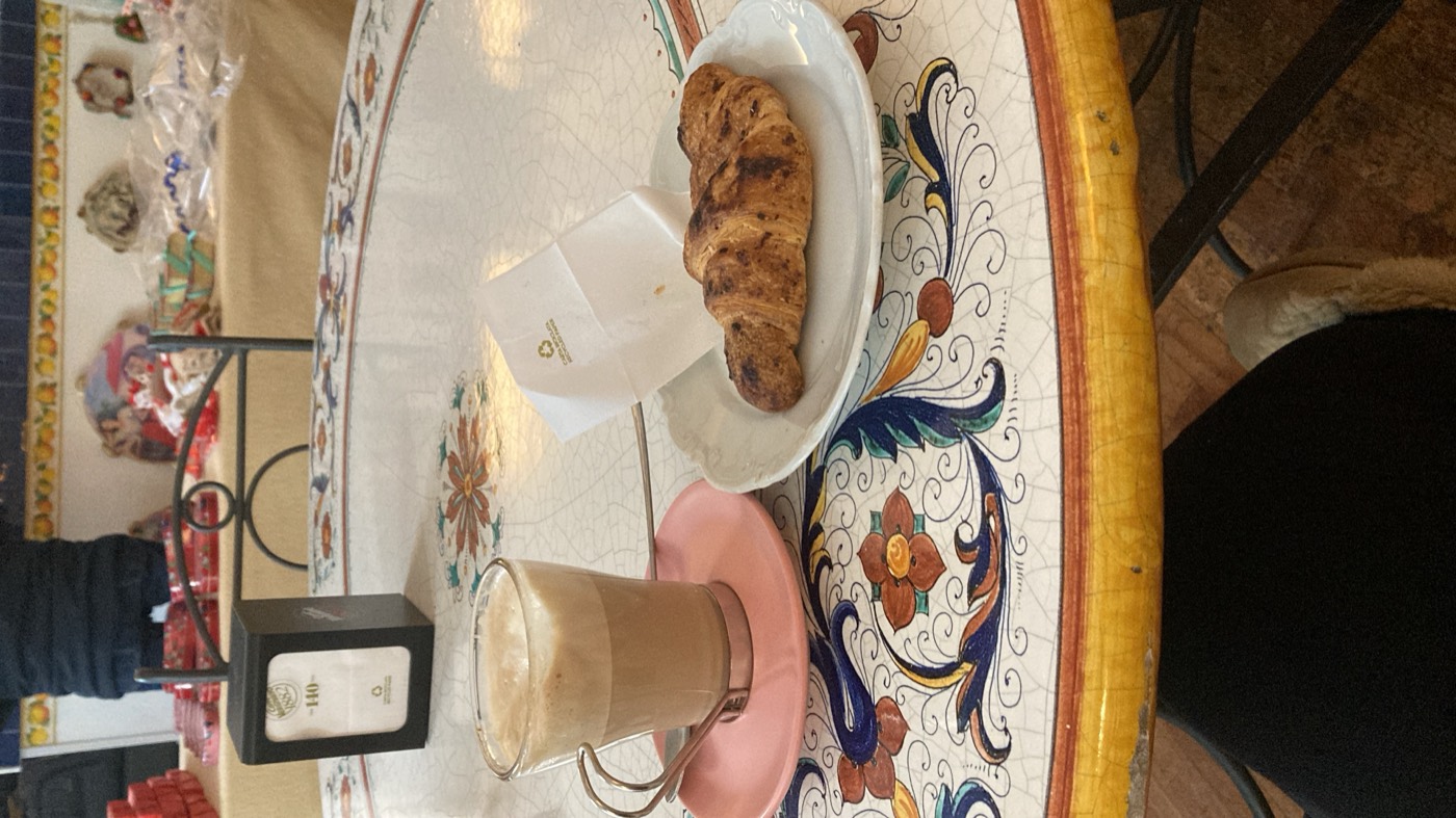 a cappuccino and a croissant on a hand painted ceramic table
