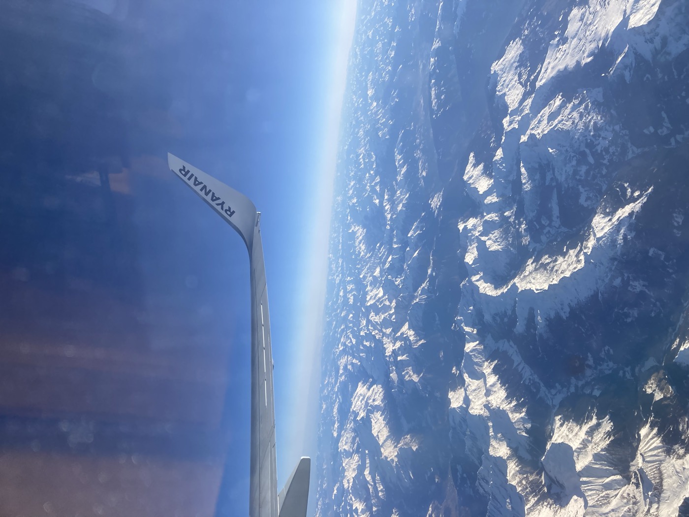 an aeroplane wing over snow covered mountains, heading home
